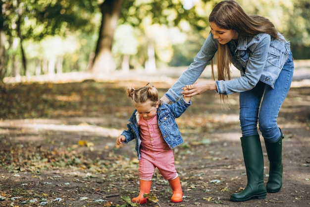 Joven madre con su pequeña hija en un parque de otoño