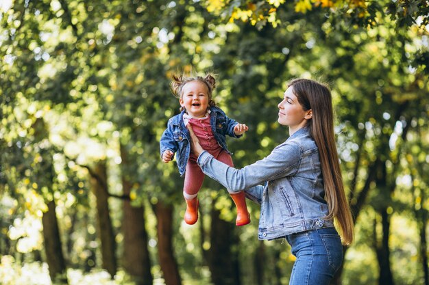 Joven madre con su pequeña hija en un parque de otoño