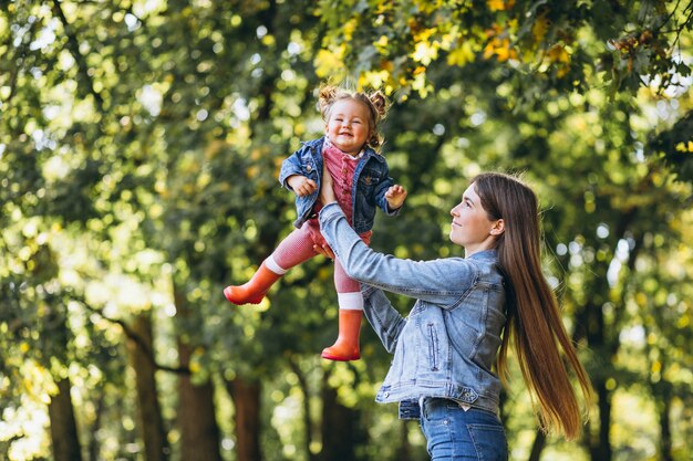 Joven madre con su pequeña hija en un parque de otoño