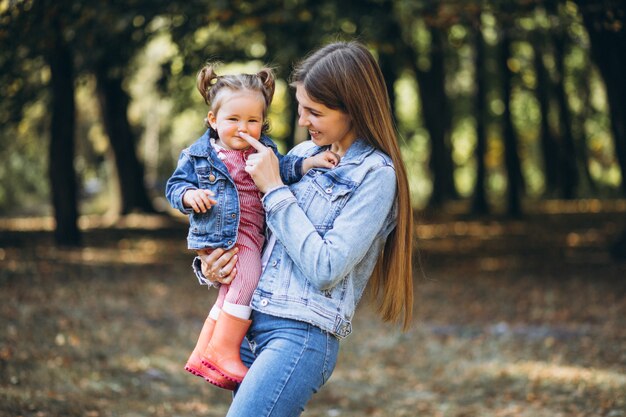 Joven madre con su pequeña hija en un parque de otoño