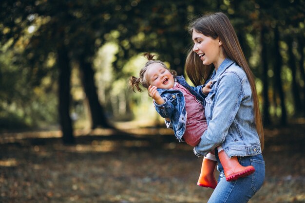 Joven madre con su pequeña hija en un parque de otoño