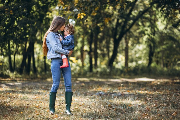 Joven madre con su pequeña hija en un parque de otoño