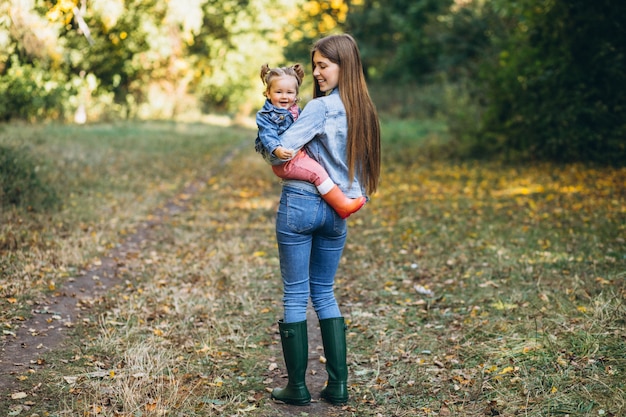 Joven madre con su pequeña hija en un parque de otoño