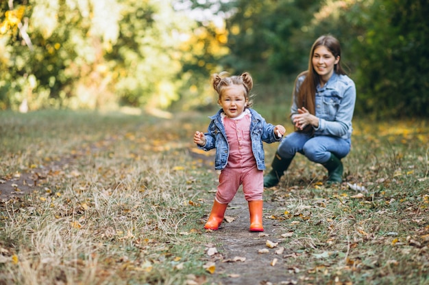 Joven madre con su pequeña hija en un parque de otoño