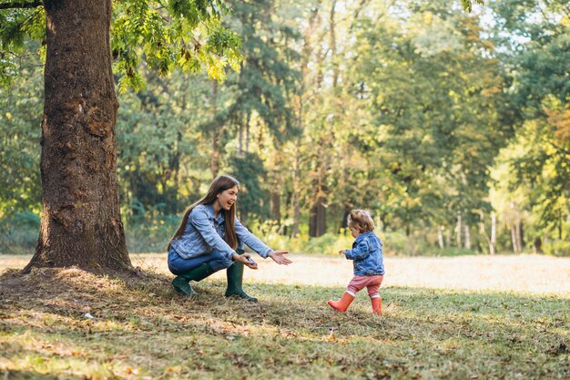 Joven madre con su pequeña hija en un parque de otoño