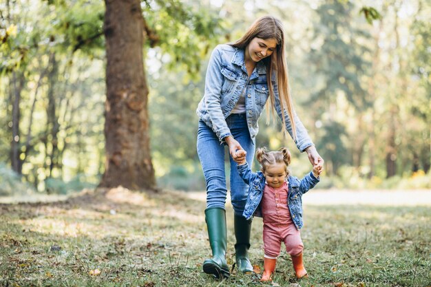 Joven madre con su pequeña hija en un parque de otoño