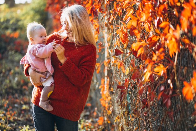 Joven madre con su pequeña hija en un parque de otoño