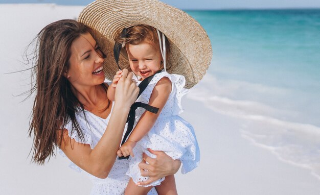 Joven madre con su pequeña hija en la playa junto al mar