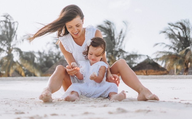 Foto gratuita joven madre con su pequeña hija en la playa junto al mar