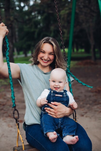 Joven madre con su pequeño bebé pasear por un parque y se regocija juntos