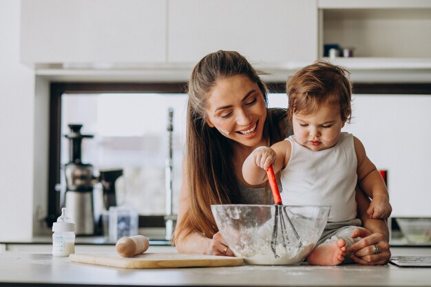 Joven madre con su pequeño hijo cocinando en la cocina