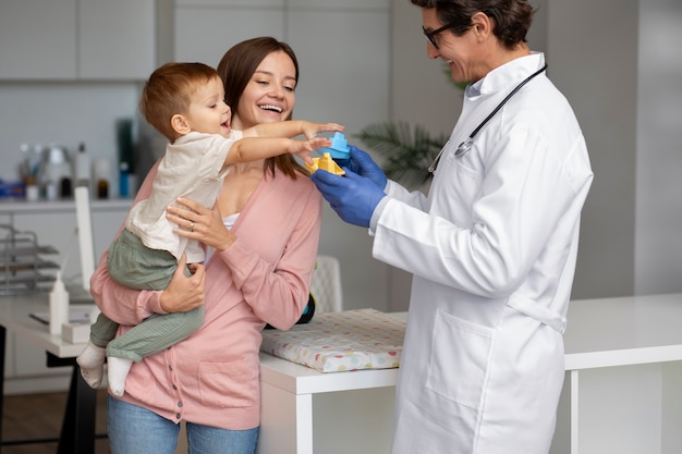 Joven madre con toddle en el pediatra para una consulta.