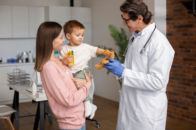 Joven madre con toddle en el pediatra para una consulta.