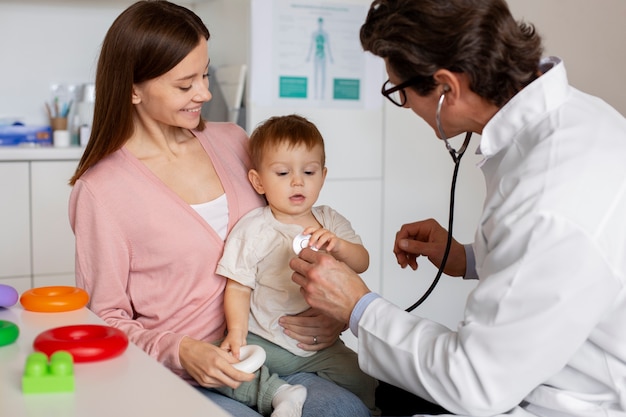 Joven madre con toddle en el pediatra para una consulta.