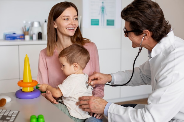 Joven madre con toddle en el pediatra para una consulta.