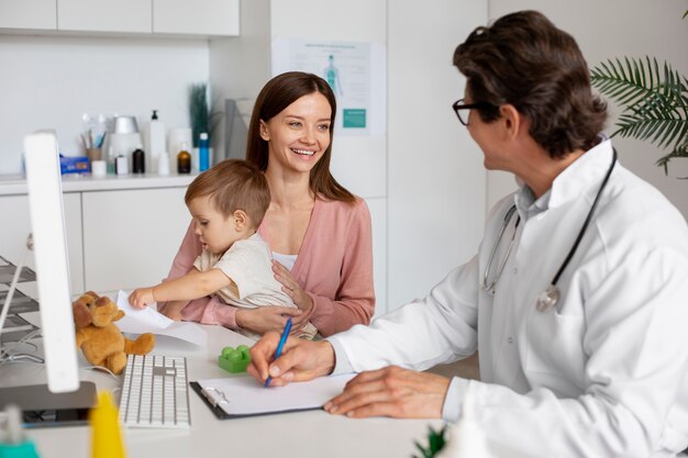 Joven madre con toddle en el pediatra para una consulta.