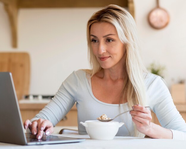 Joven madre trabajando y desayunando en casa