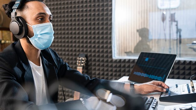 Joven con máscara médica trabajando en una estación de radio