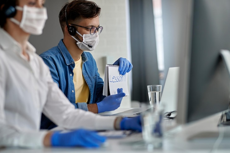 Foto gratuito joven con mascarilla protectora mientras imparte clases en línea por computadora durante la epidemia de coronavirus