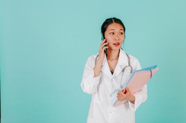 Joven médico asiático hablando por teléfono