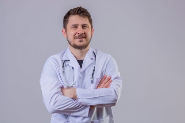 Joven médico con bata blanca y estetoscopio con confianza con los brazos cruzados 1