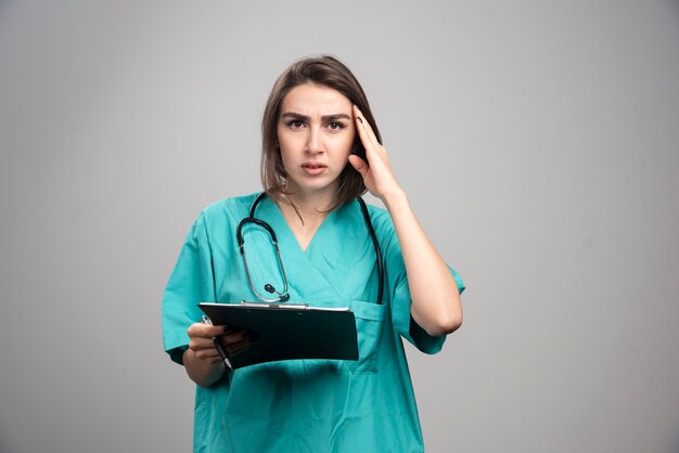 Joven médico con dolor de cabeza sobre fondo gris. Foto de alta calidad