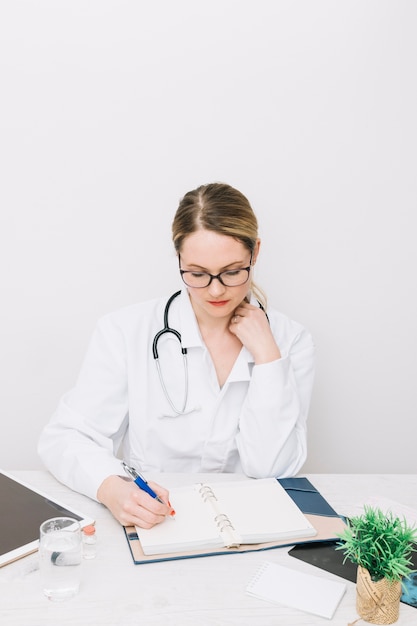 Joven médico escribiendo en el cuaderno