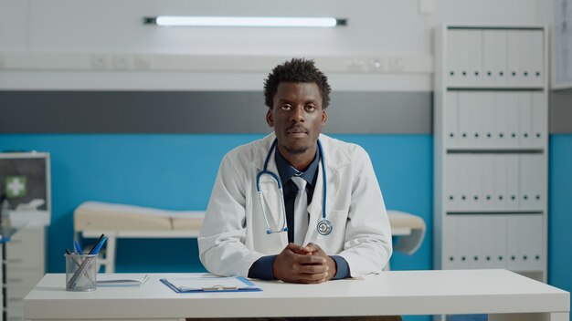 Joven médico hablando por videoconferencia con el paciente para consulta remota en línea mientras está sentado en el escritorio en el gabinete. Medic utilizando la comunicación por Internet para el tratamiento de telemedicina