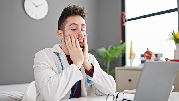 Foto gratuita joven médico hispano quitándose las gafas estresado en la clínica