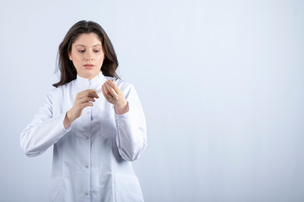 Foto gratuita joven médico con jeringa preparándose para la inyección en la pared blanca.