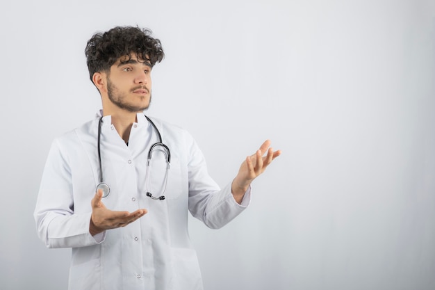 Joven médico levantando las manos y mirando a otro lado.