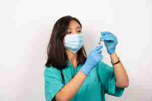 Foto gratuita joven médico en máscara médica y guantes preparando jeringa sobre fondo blanco. foto de alta calidad