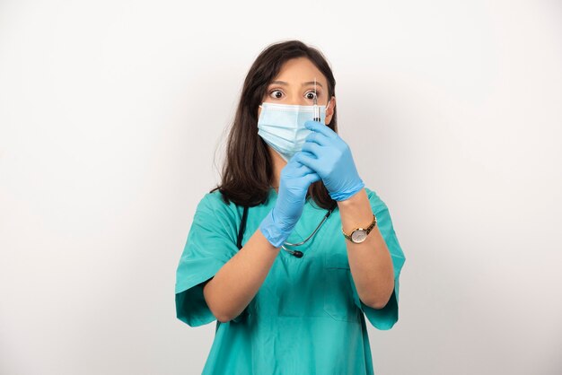 Joven médico con máscara médica preparando jeringa para inyección sobre fondo blanco. Foto de alta calidad