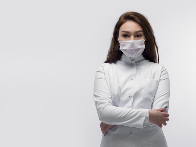 Joven médico con máscara protectora blanca con las manos cruzadas