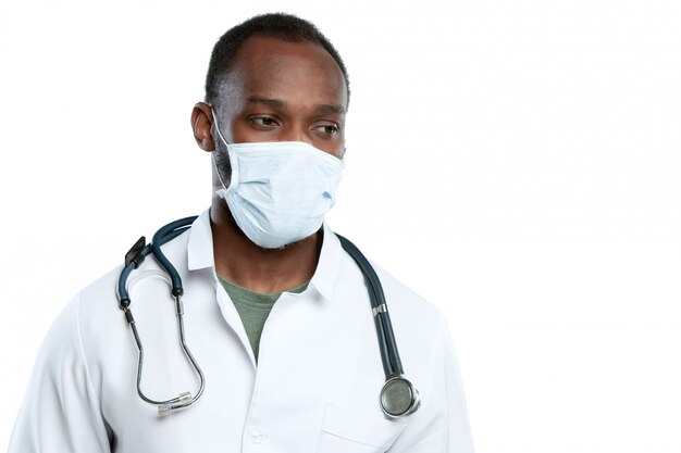 Joven médico masculino con estetoscopio y mascarilla aislado en blanco