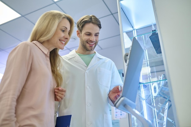 Joven médico masculino mostrando algo al visitante y luciendo involucrado