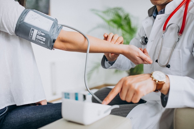 Joven médico masculino con paciente medir la presión sanguínea