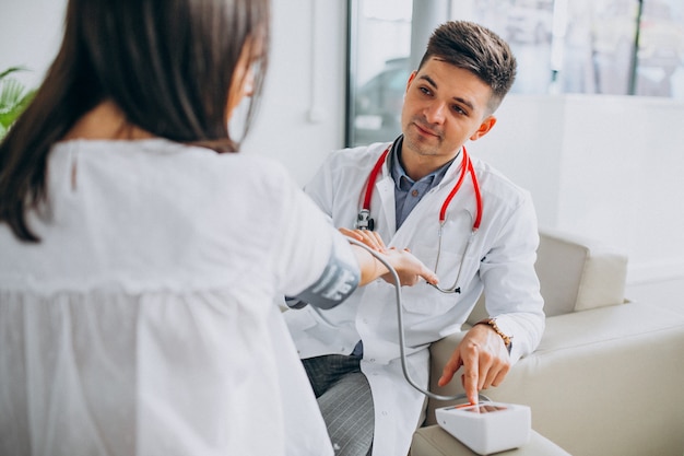 Foto gratuita joven médico masculino con paciente medir la presión sanguínea