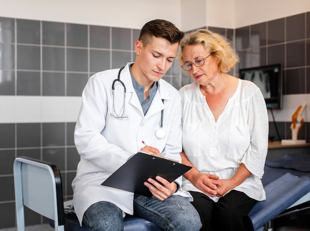 Foto gratuita joven médico mostrando resultados a mujer senior