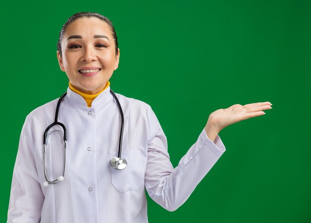 Joven médico presenta espacio de copia con el brazo de la mano sonriendo