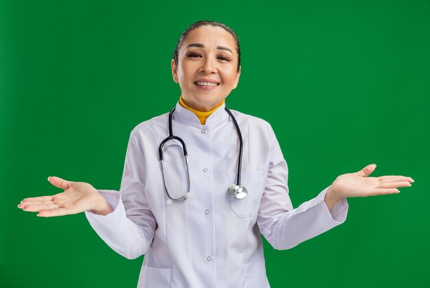 Joven médico sonriendo extendiendo los brazos a los lados