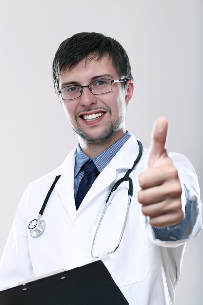 Joven médico sonriente con los pulgares para arriba