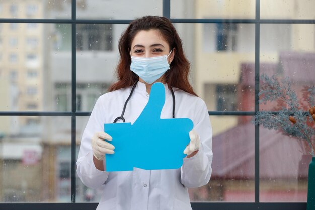 Joven médico sosteniendo una burbuja de idea de papel en forma de pulgar hacia arriba y sonriendo Foto de alta calidad