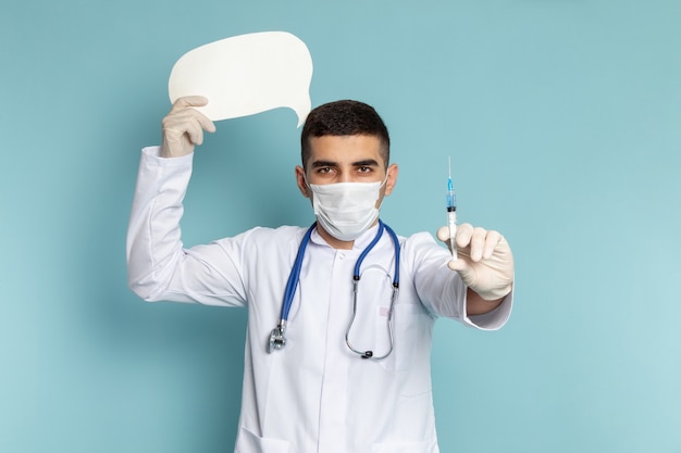 Joven médico en traje blanco con estetoscopio azul con inyección y trabajo de letrero blanco