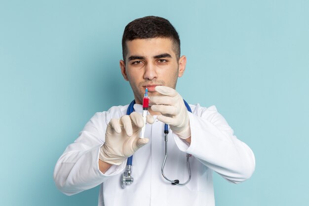 Joven médico en traje blanco con estetoscopio azul con inyección