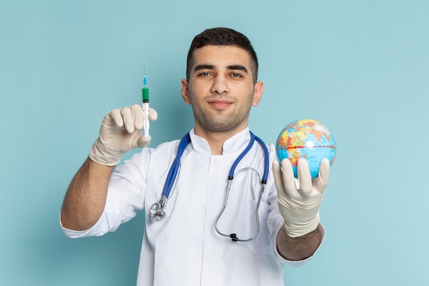 Joven médico en traje blanco con estetoscopio azul con inyección