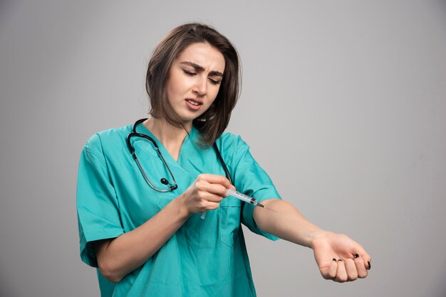 Joven médico en uniforme inyectándose con una jeringa. Foto de alta calidad