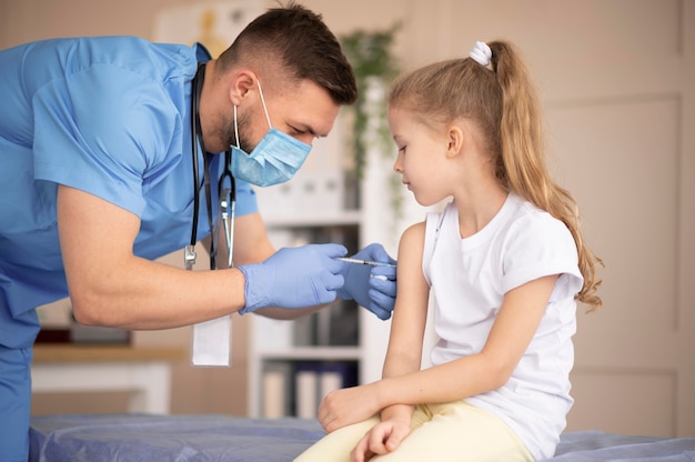 Joven médico vacunando a una niña