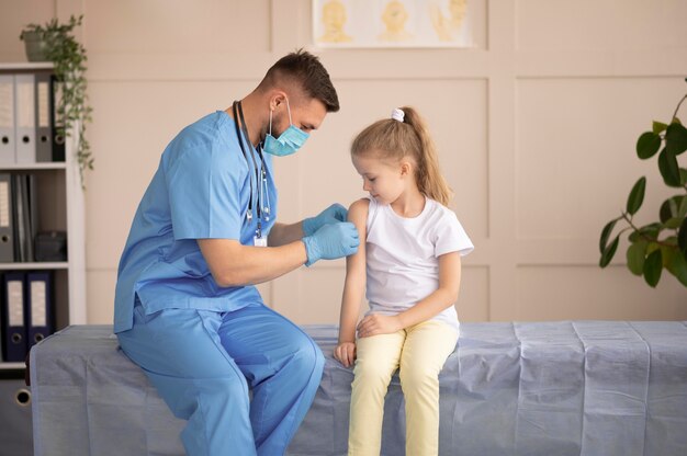 Joven médico vacunando a una niña