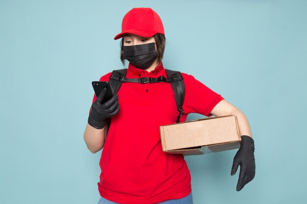 joven mensajero en polo rojo gorra roja máscara protectora estéril negra mochila negra con paquete en azul